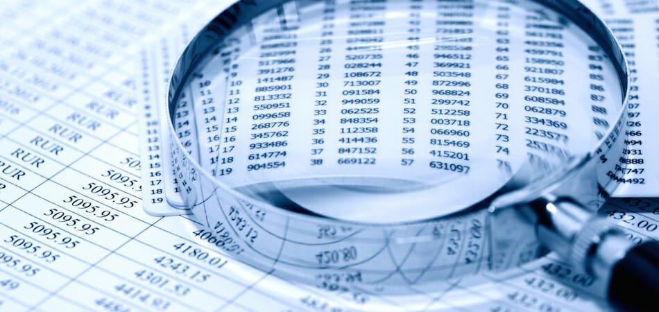 magnifying glass lying on top of financial statements