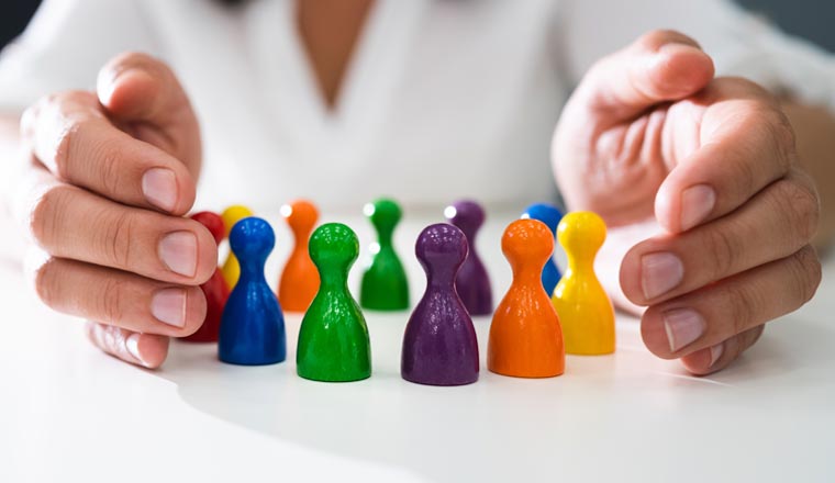 hands grouped around multicolored game pieces