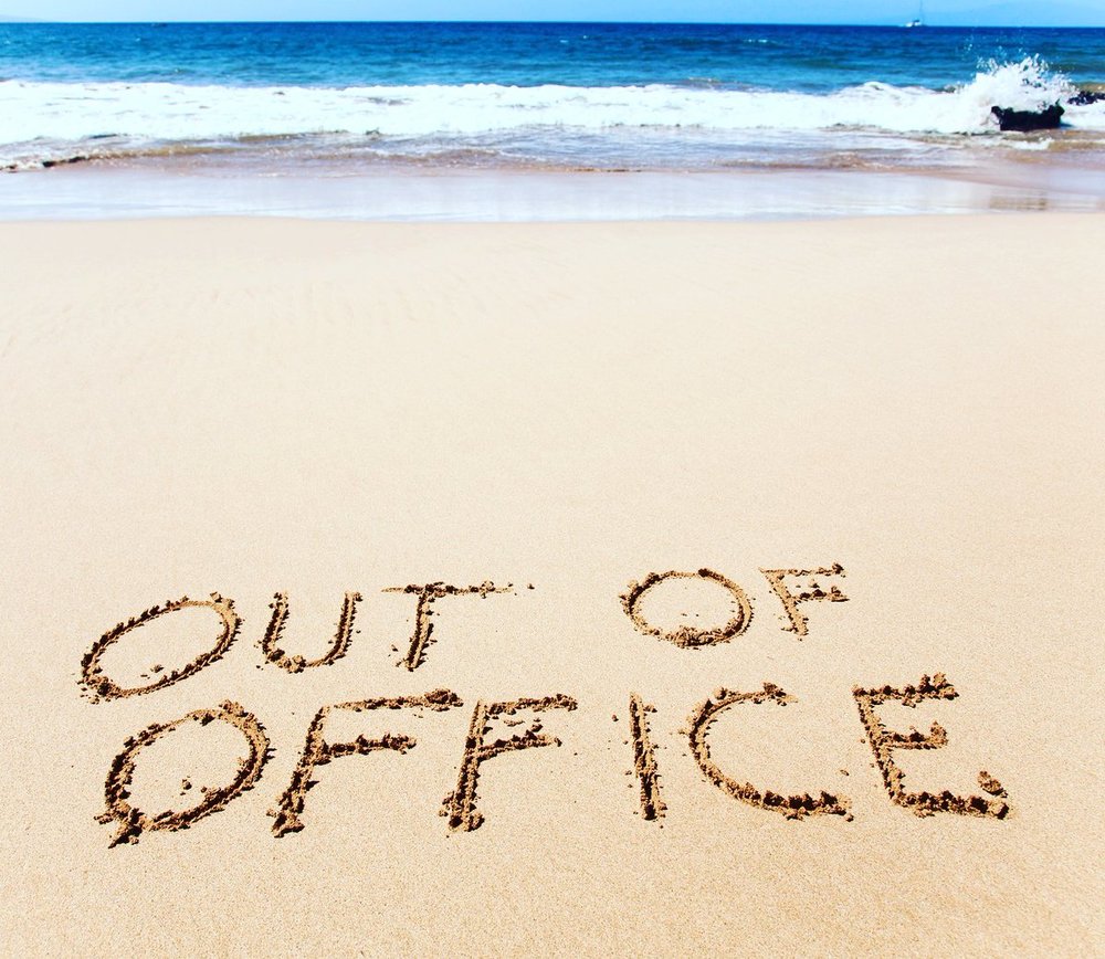 beach with words "out of office" written in the sand