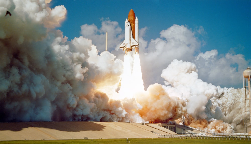 the space shuttle launches in a cloud of steam and smoke