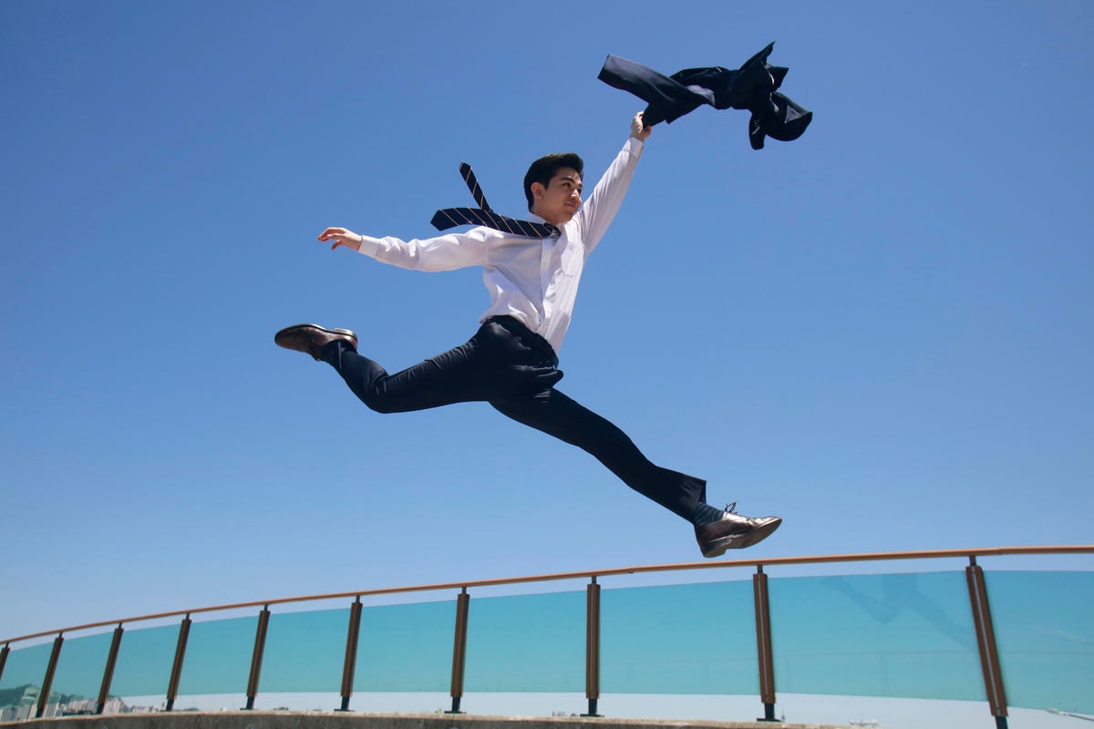 person leaping over a fence and throwing a suit jacket in the air
