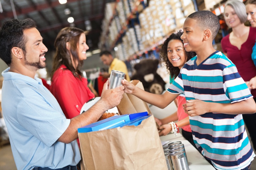 adults and children sort and bag up donations at a food bank