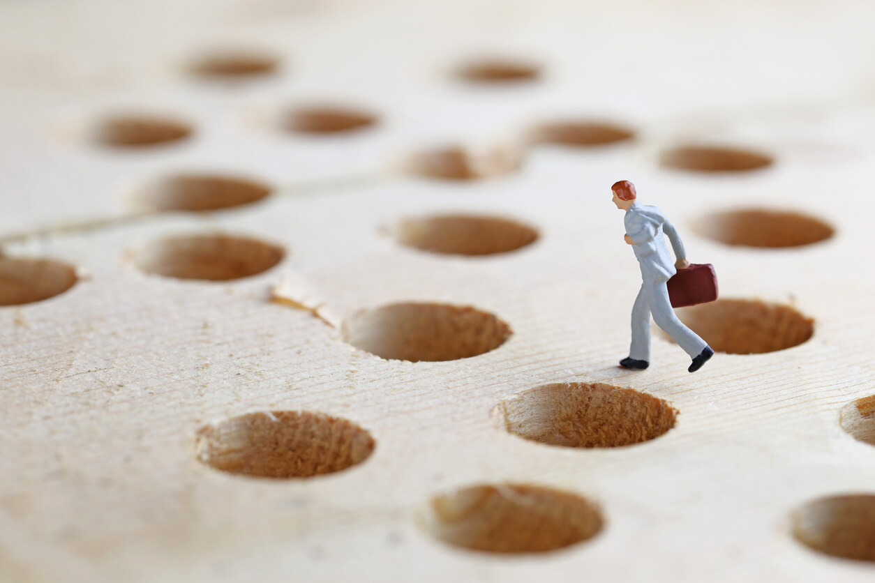 a small figure of a businessperson carrying a briefcase and surrounded by holes