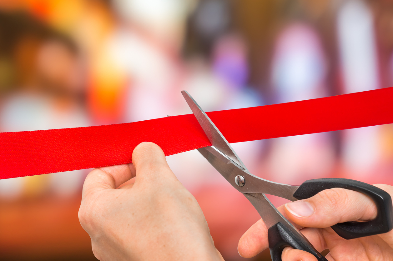 a person prepares to cut a ribbon to open a business