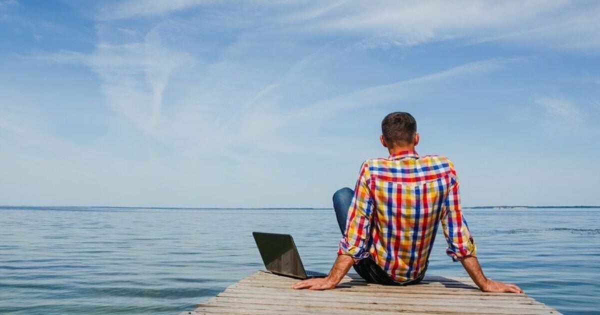 a person sits on the end of a dock with their laptop nearby