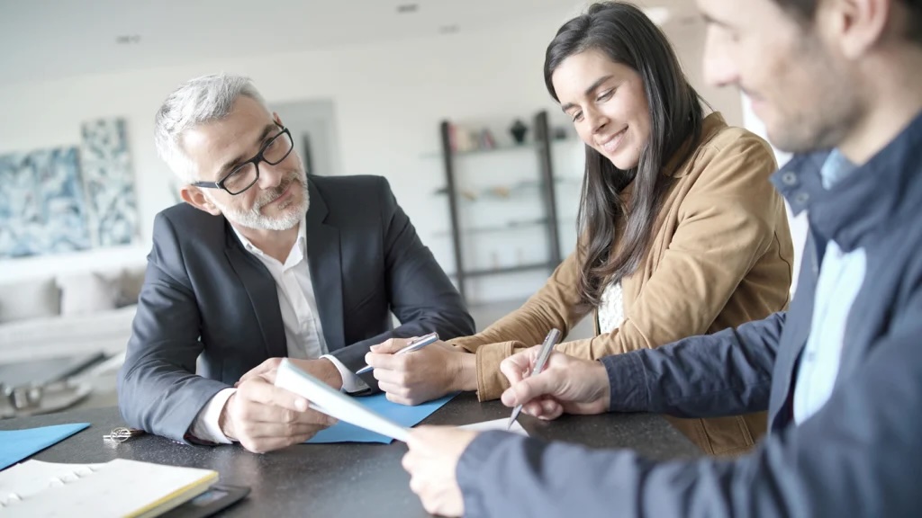 a smiling couple sign documents to purchase a business