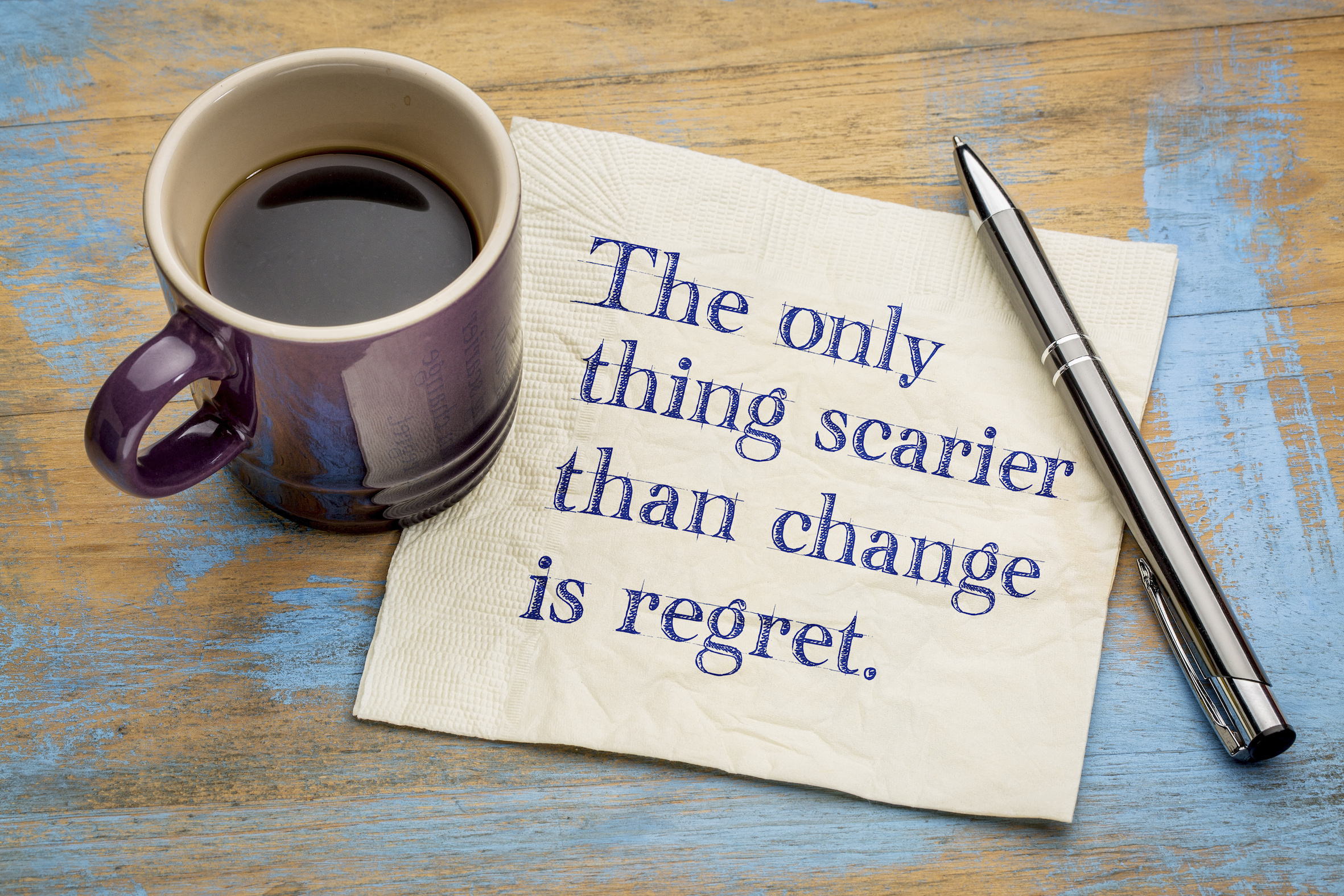 a mug of coffee sits next to a napkin containing the text "the only thing scarier than change is regret"