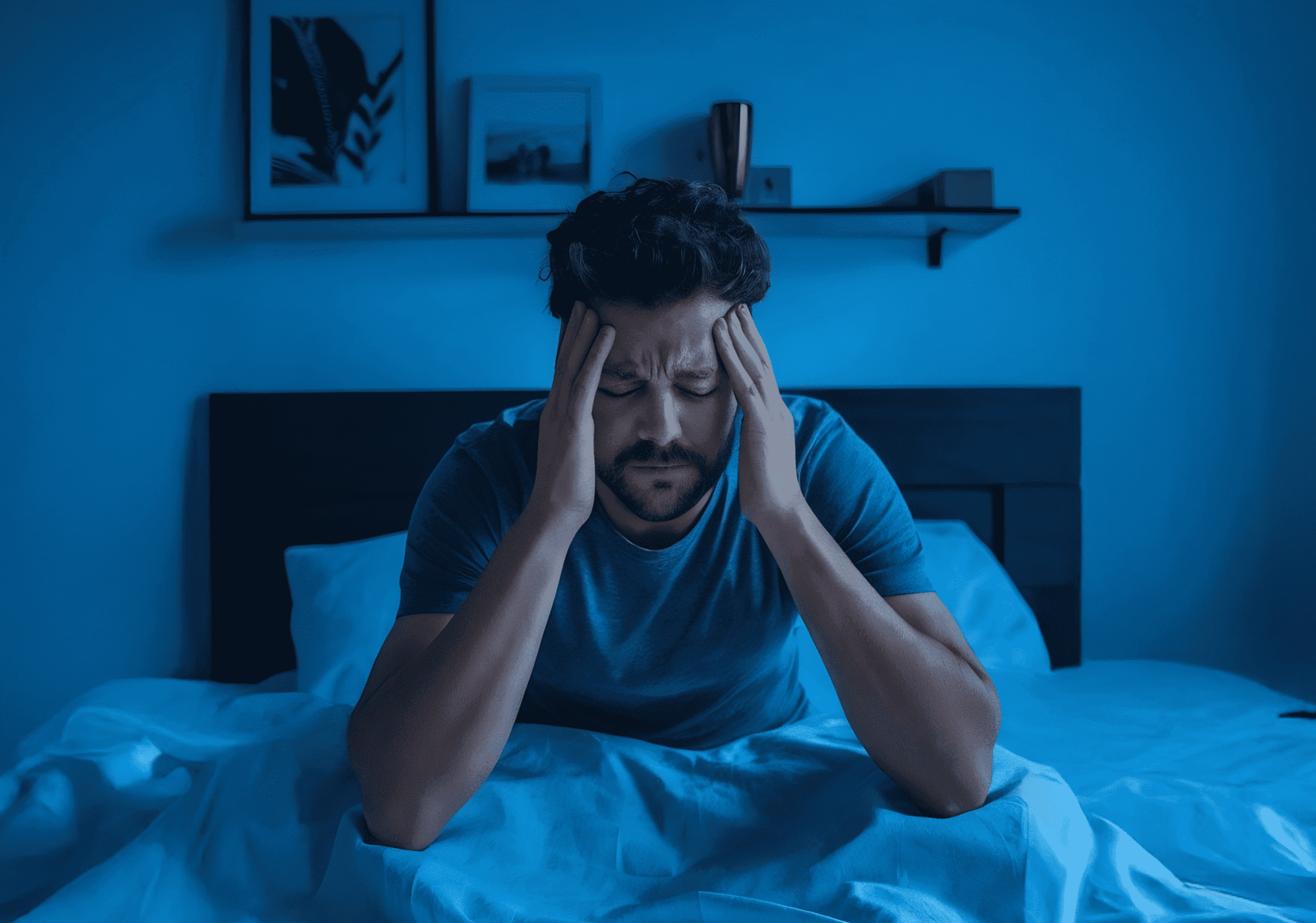 a man sits up in bed, anxious and unable to sleep