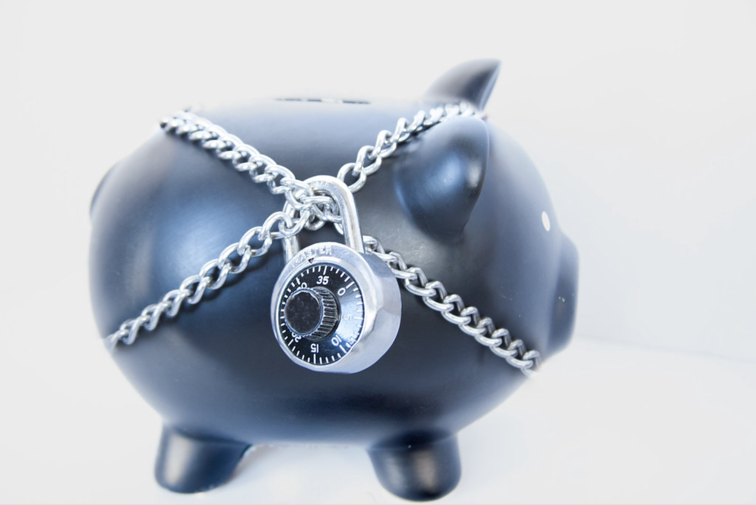 a steel-gray piggy bank with chains and a padlock around it ("Financial Security" by perspec_photo88 is licensed under CC BY-SA 2.0)